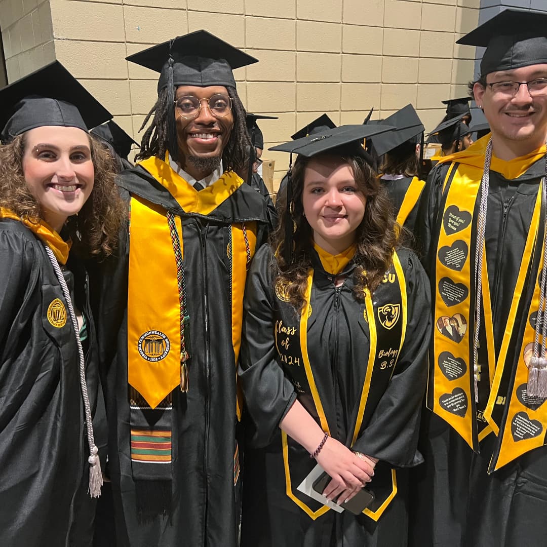 Students smiling for picture dressed up in graduation regalia.
