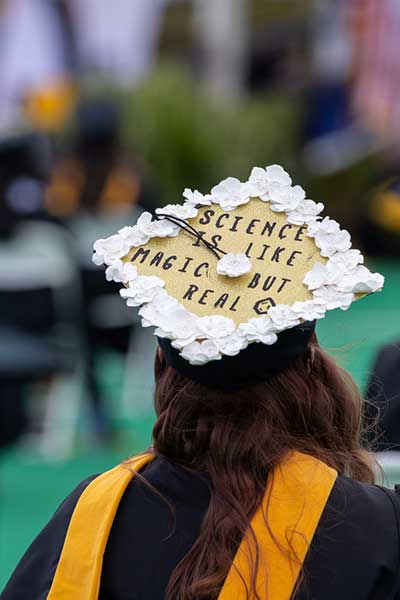 a v. c. u. student at a commencement ceremony wearing a graduation cap that reads 